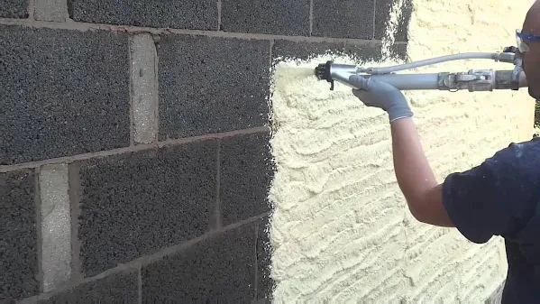 Spray rendering being applied to exterior wall surface